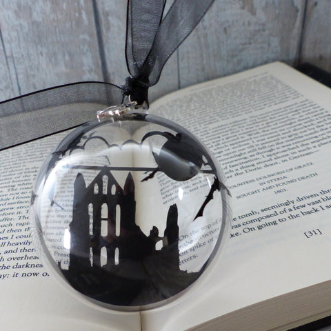 black paper cut of Whitby abbey encased in plastic bubble decorated with bats