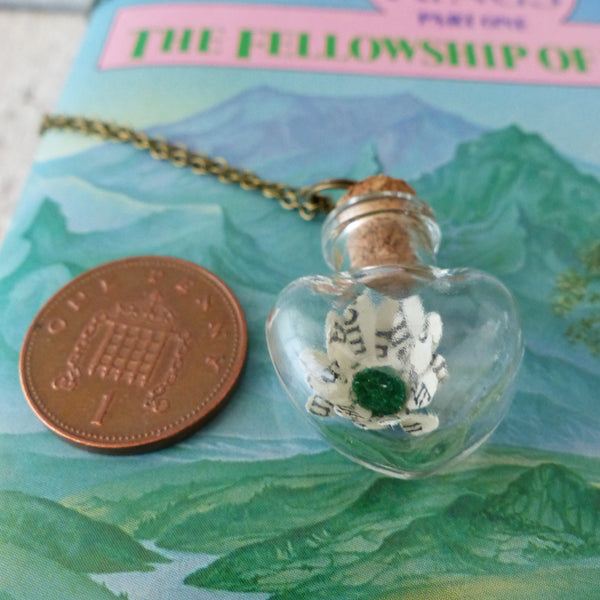 Book daisy in bottle next to 1 pence piece for scale